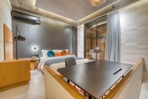 a bedroom with a bed and a table in it at Tegeh Townhouse Complex Modern 1BR In Uluwatu in Ungasan