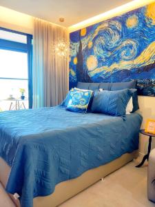 a bedroom with a blue bed with a painting on the wall at VAN GOGH-SE Studio privado com Rooftop, garagem, piscina aquecida in Salvador