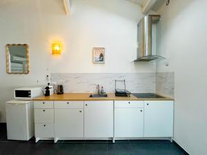 ヴィルールバンヌにあるPalm - appartement 5 personnes - check in h24 - wifiの白いキャビネットとシンクのあるキッチン