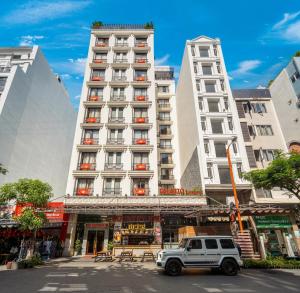 een witte SUV geparkeerd voor een hoog gebouw bij Palazzo Luxury Hotel & Bistro - Central My Khe Beach Walking Street in Da Nang