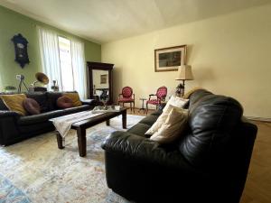 a living room with a black leather couch and a coffee table at Casa Crown in Sighişoara
