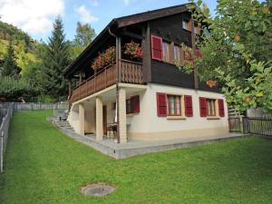 a house with red shutters and a green yard at Glacier Views & Ski Trails in Blatten bei Naters