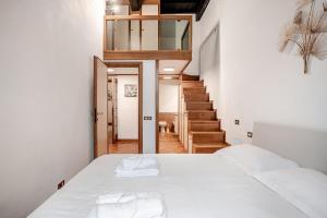 ein Schlafzimmer mit einem Bett mit weißer Bettwäsche und einer Treppe in der Unterkunft Eleganza e charme a due passi da Piazza di Spagna in Rom