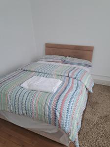 a bed with a striped comforter on top of it at London Ilford town house in Ilford