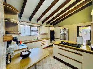 a large kitchen with white cabinets and a wooden table at Villa Picasso - 2 Bed Villa in Johannesburg
