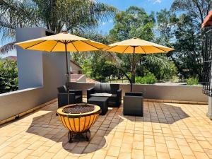 a patio with two umbrellas and a table and chairs at Villa Picasso - 2 Bed Villa in Johannesburg
