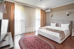 a bedroom with a large white bed and a television at Sacvoyage Hotel in Almaty