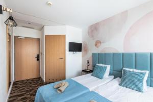 a bedroom with a bed with a blue headboard at Sapphire Hotel Rooms Lechicka in Poznań