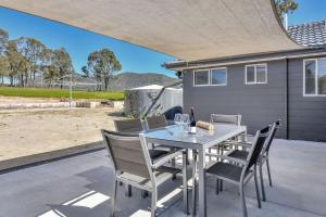 a dining table and chairs on a patio at Andres Farm Cottage in Broke +24 photos