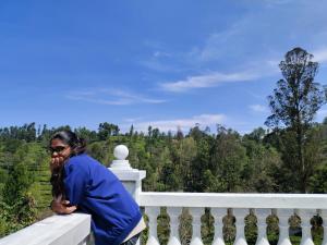 a woman sitting on a fence talking on a cell phone at Pear Tree Luxe Entire 3BHK Villa - Only For Family in Kotagiri