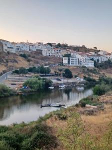 a river with boats in the water and buildings at Eleven Castelo in Mértola