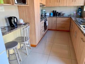 a kitchen with wooden cabinets and a table and chairs at Bisho Grand Escape in Bisho +2 photos