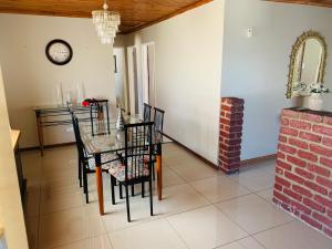 a dining room with a table and chairs and a clock at Bisho Grand Escape in Bisho