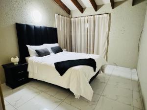 a bedroom with a large bed with a black headboard at Villa Picasso - 3 Bed Villa in Johannesburg +31 photos