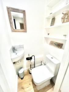 a white bathroom with a toilet and a sink at Large one bedroom beach apartment in Bel Royal