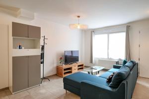 a living room with a blue couch and a tv at Bienvenue - 500 m de la plage in Courseulles-sur-Mer