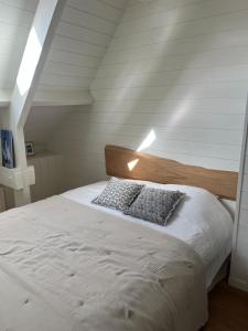 een slaapkamer met een wit bed met een houten hoofdeinde bij La Maison Rose in Saint-Armel