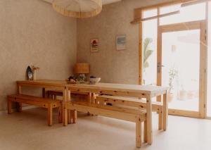 a dining room with a wooden table and benches at Malibu Surf House in Tamraght Ouzdar