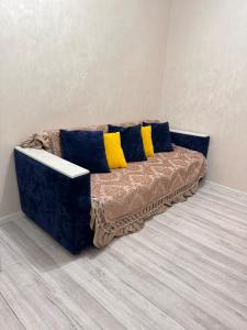 a couch with blue and yellow pillows in a room at Толебаева Центр Талдыкорган in Taldykorgan +3 photos
