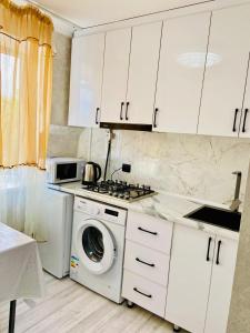 a kitchen with a washing machine and a microwave at Толебаева Центр Талдыкорган in Taldykorgan