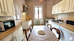 a kitchen with a table with chairs and a microwave at Le Pavillon des Dames in Migé +9 photos