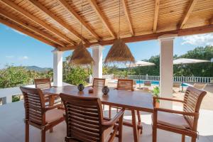 a wooden dining table and chairs under a wooden pergola at Can Joan Durban in Sant Joan de Labritja