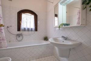 een witte badkamer met een wastafel, een bad en een wastafel bij Trilocale Fiordaliso in Stintino +15 foto's