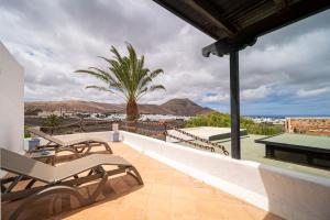 a patio with chairs and a table and a palm tree at Casa de Hilario in Yaiza