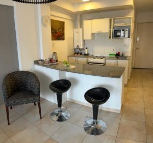 Una cocina con encimera y dos taburetes de bar. en Rosario frente al Rio, en Rosario