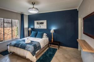a bedroom with a bed with a blue wall at Dew Drop Inn in Nelspruit