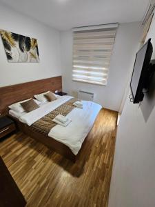 a bedroom with a bed and a flat screen tv at Apartman Žaxtef Wellness&Spa u ceni in Zlatibor