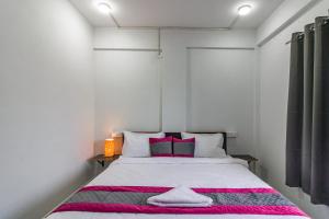 ナーグプルにあるHotel NS Villaのピンクをアクセントにした白い大型ベッド付きのベッドルーム1室 +2枚の写真