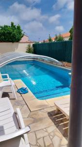 una piscina con due sedie e una piscina di Villa Climatise Avec Grande Piscine a Saint-Laurent-de-la-Salanque