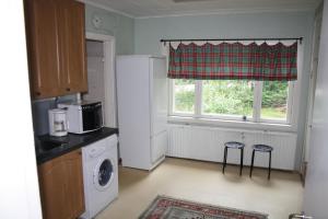 a kitchen with a refrigerator and two stools in front of a window at Villa Vanha Valko in Lovisa