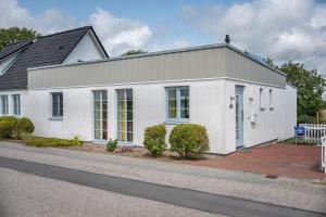 Ein weißes Haus an der Seite einer Straße in der Unterkunft Bi Pasders in Nordstrand