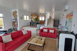 a living room with two red couches and a table at Casa Condor - Moradia com piscina a 5 min da praia in Lourinhã