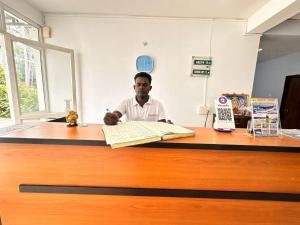 a man sitting at a desk with a book at SS Grand with swimming pool in Puducherry +30 photos
