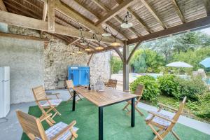 eine Terrasse mit einem Holztisch und Stühlen unter einer Holzdecke in der Unterkunft Maison de Campagne à Cunèges in Cunèges