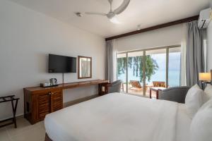 a bedroom with a large white bed and a balcony at Nungwi Dreams by Mantis in Nungwi