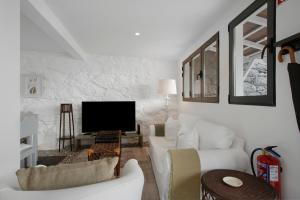 a living room with two white couches and a tv at The Village Loft in Caniço