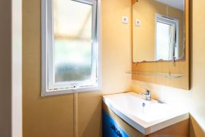 une salle de bain avec un lavabo et une fenêtre dans l'établissement Mobilhome La Clairière, à Saint-Pompont 13 autres photos