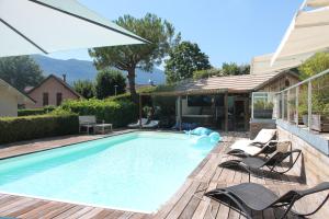a swimming pool with chairs and a house at Au Cœur De La Riviera Des Alpes T2 in Brison-Saint-Innocent