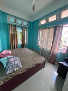 a bedroom with a bed with blue walls and windows at Sunrise Homestay in Jāmb