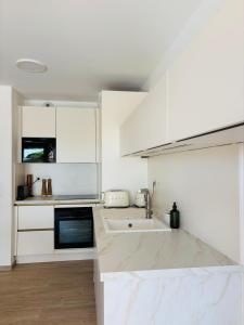 eine weiße Küche mit weißen Schränken und einer Spüle in der Unterkunft Appartement T2 chambre plus cabine, terrasse vue piscine in Bormes-les-Mimosas