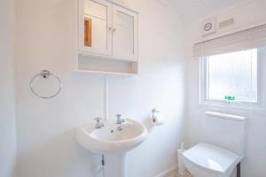 a white bathroom with a sink and a toilet at Lakeside 1, White Cross Bay, Windermere in Windermere +7 photos
