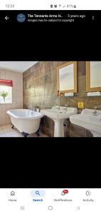 a bathroom with two sinks and a bath tub at The Tennants Arms Kilnsey in Kilnsey