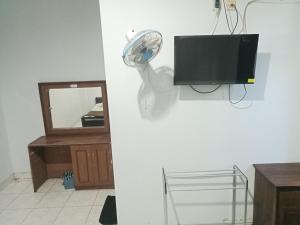 a room with a fan and a tv on a wall at Hotel Taman Rai in Tabanan