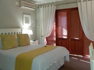 a bedroom with a bed with white and yellow sheets at Cranberry Cottage in Kathu +53 photos
