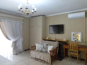 a living room with a chair and a desk and a television at Cranberry Cottage in Kathu