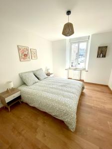 a white bedroom with a bed and a window at Les Clés de Saint-Pierre in Saint-Pierre-Église